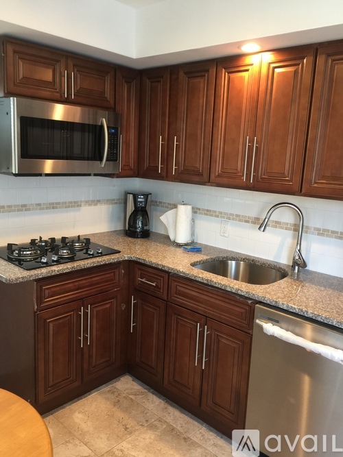 A kitchen with brown cabinets and a stainless steel refrigerator.