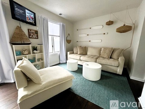 A living room with a white couch and a TV mounted on the wall.