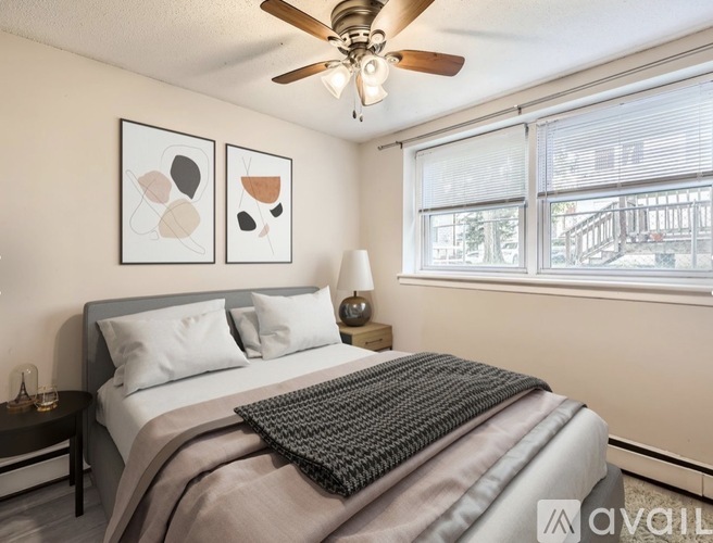 A bedroom with a bed, a ceiling fan, and two wall art pieces.