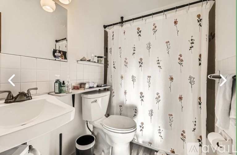 A white bathroom with a floral shower curtain.
