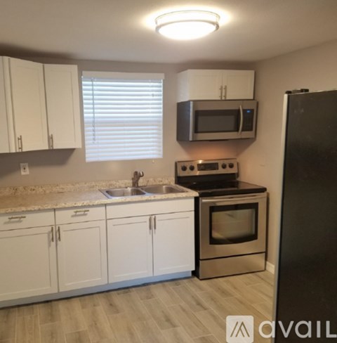 A kitchen with white cabinets and a black refrigerator.