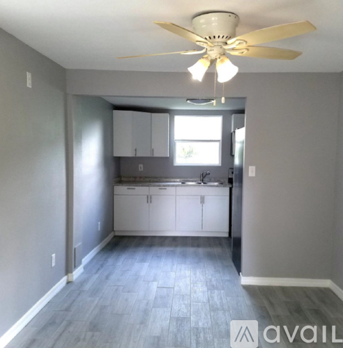 A kitchen with a fan on the ceiling and cabinets below a window.