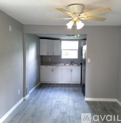 A kitchen with a fan on the ceiling and cabinets below a window.