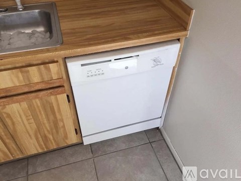 A white dishwasher is built into a wooden cabinet in a kitchen.