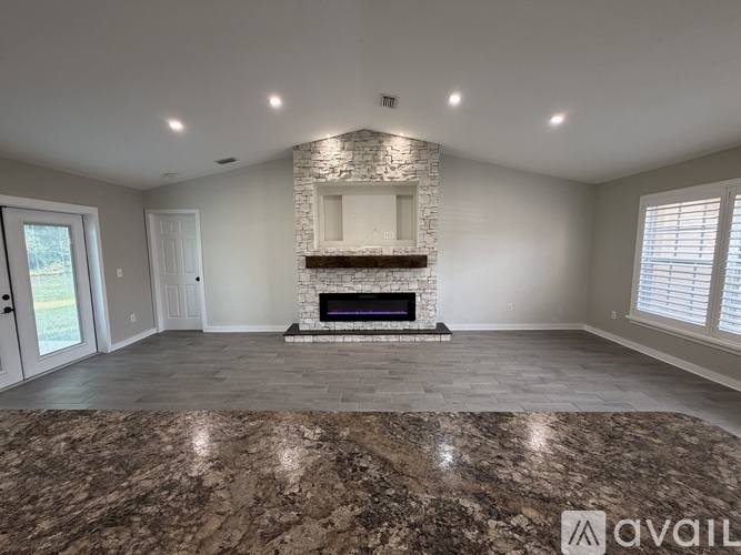 A spacious room with a stone fireplace and marble flooring.
