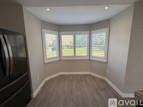 A kitchen with a refrigerator and a window with shutters.