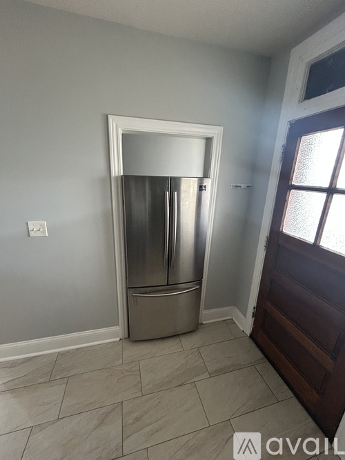 A kitchen with a stainless steel refrigerator and a tiled floor.