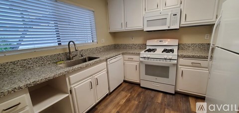 A kitchen with white cabinets and appliances.