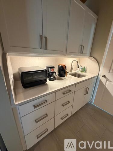 A kitchen with white cabinets and a black toaster on the counter.