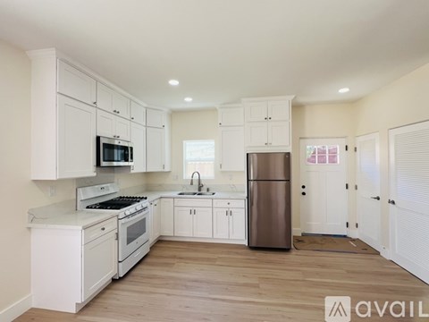 A kitchen with white cabinets and appliances is available for rent.