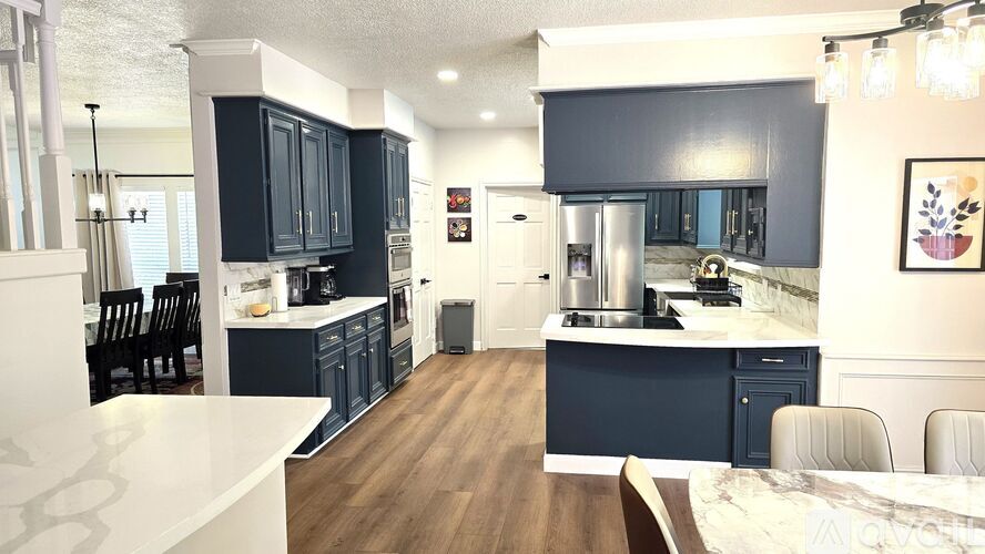 A modern kitchen with dark blue cabinets and a marble countertop.