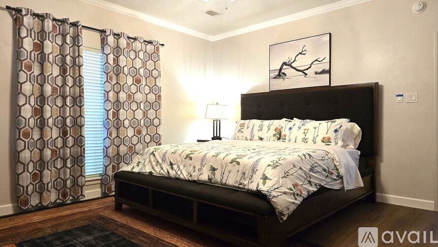 A bedroom with a large bed and a window with curtains.