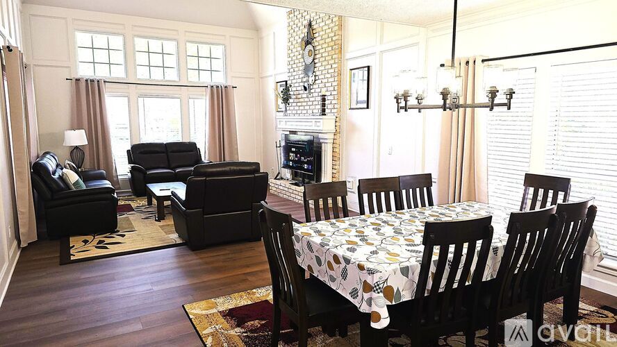 A living room with a black sofa, a black chair, a black couch, a black armchair, a black coffee table, a black dining table with six chairs, a white tablecloth with black and white polka