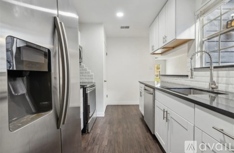 A modern kitchen with a stainless steel refrigerator and wooden flooring.