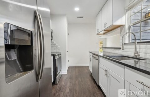 A modern kitchen with a stainless steel refrigerator and wooden flooring.