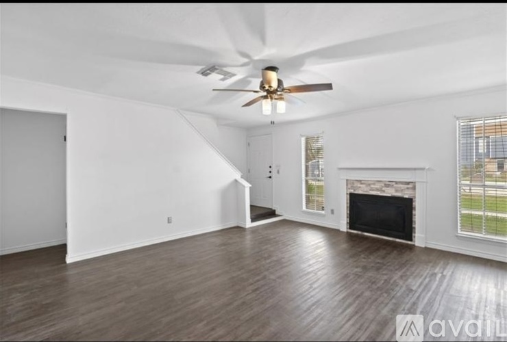 A spacious living room with a fireplace and a ceiling fan.