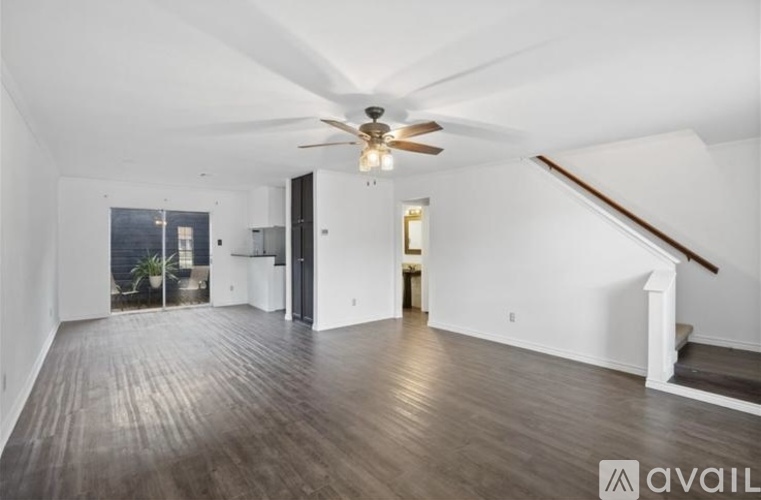A spacious room with wooden flooring and a ceiling fan.