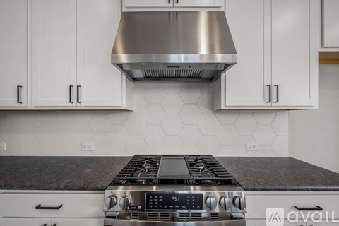 A modern kitchen with a stove top oven and white cabinets.