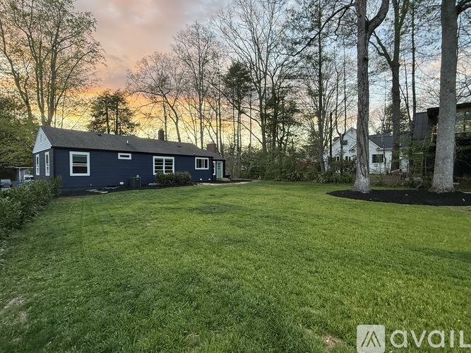 A house with a blue exterior is surrounded by a grassy lawn and trees.