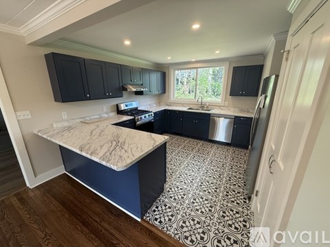 A kitchen with black cabinets and a marble island.