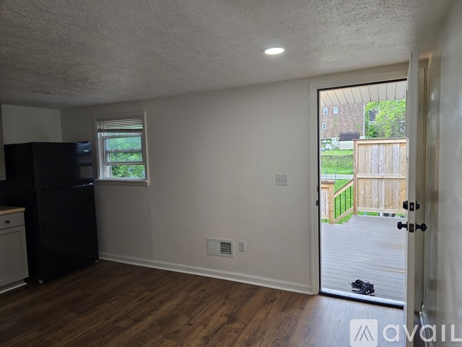 A kitchen with a black fridge and a wooden floor.