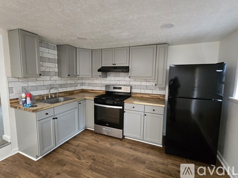 A kitchen with a black fridge and stove top oven.