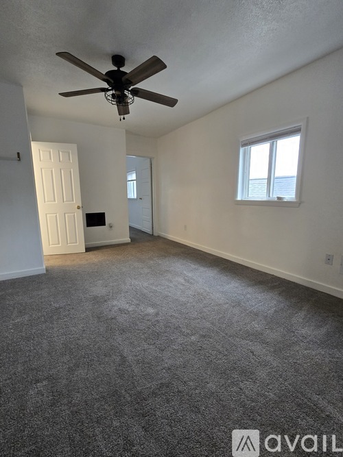 A room with a ceiling fan and carpeted floor.