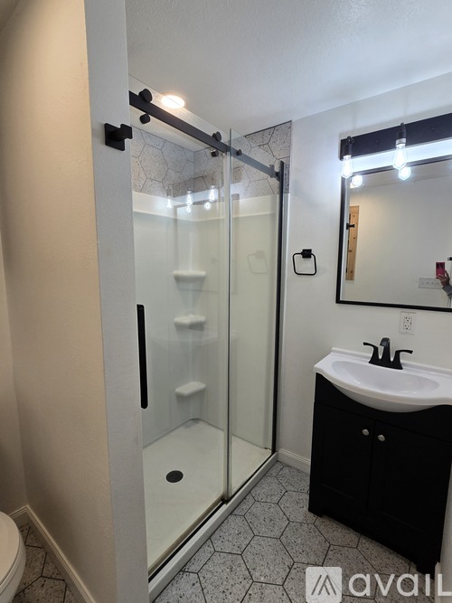A bathroom with a sink, mirror, and shower.
