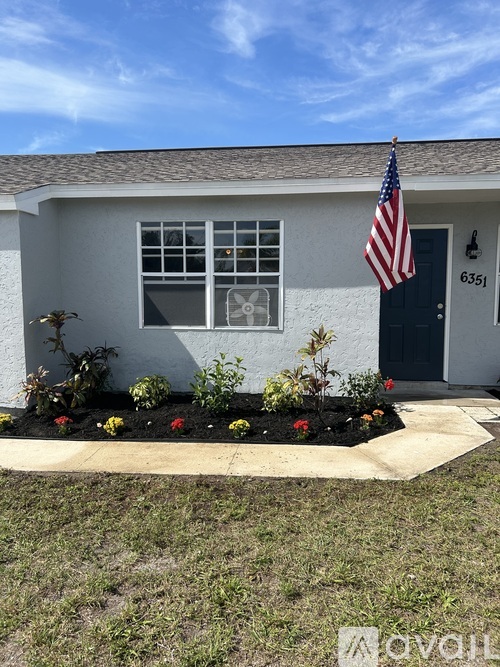 A house with a flag on the front and a number 6351 on the door.