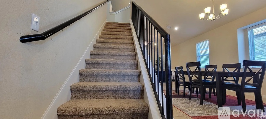 A staircase with a carpeted runner and a black handrail.