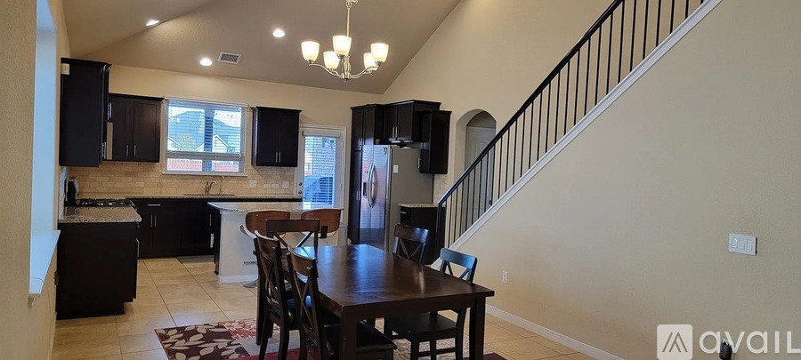 A kitchen with a dining table and chairs in the middle of the room.