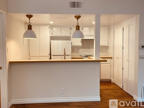 A kitchen with white cabinets and a wooden island.