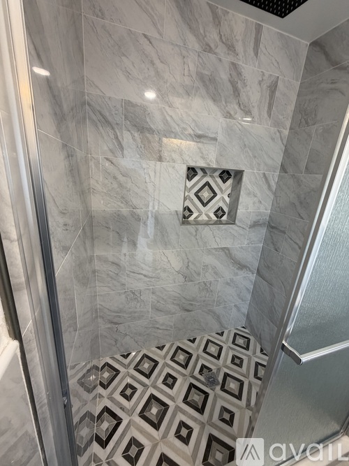 A shower with a tiled floor and walls.