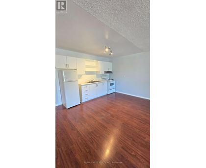 A kitchen with white appliances and wooden floors.