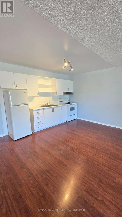 A kitchen with white appliances and wooden floors.