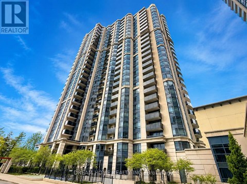 A tall residential building with balconies and a fence in front.