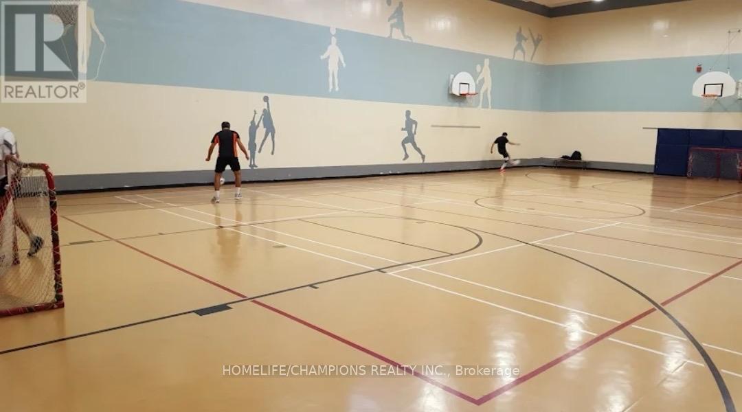 A gym with a wall mural of basketball players and a basketball court with players on it.