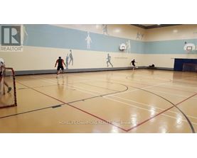 A gym with a wall mural of basketball players and a basketball court with players on it.