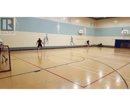 A gym with a wall mural of basketball players and a basketball court with players on it.