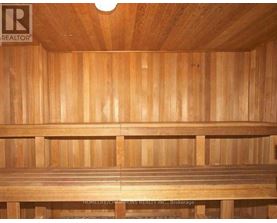 A wooden sauna with a bench and a light on the ceiling.
