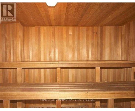 A wooden sauna with a bench and a light on the ceiling.