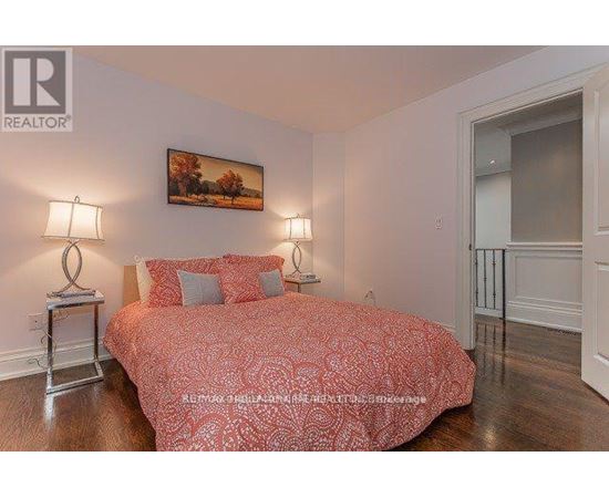 A bedroom with a large bed and a painting on the wall.