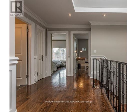 A spacious hallway with wooden floors and white walls.