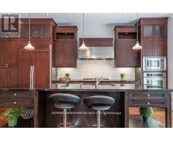 A kitchen with wooden cabinets and a black bar stool.