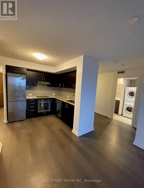 A kitchen with dark wood floors and stainless steel appliances.