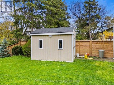 A small shed sits in a grassy backyard.