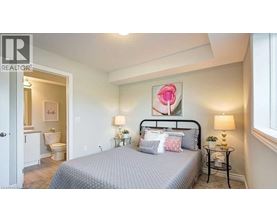 A bedroom with a bed, nightstands, and a painting of a rose.