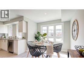 A dining room with a table set for four and a clock on the wall.