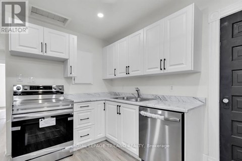 A white kitchen with a stainless steel dishwasher and oven.