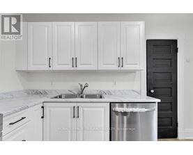 A kitchen with white cabinets and a black door.